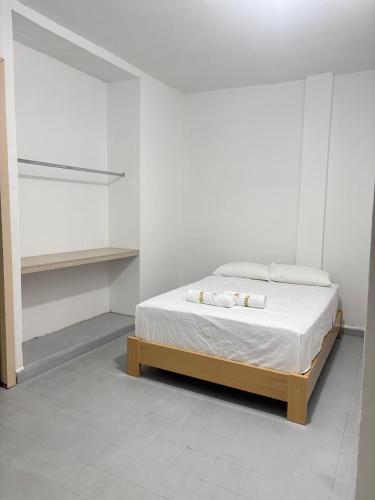 a white bedroom with a bed with white sheets at Hotel Jemara in San Gil