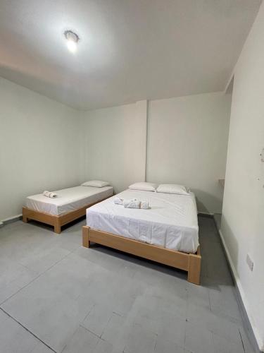 two beds in a room with white walls at Hotel Jemara in San Gil