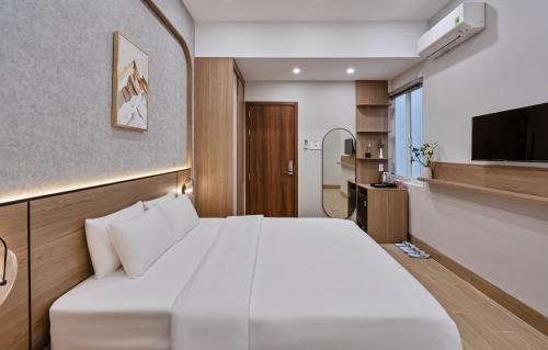 a bedroom with a large white bed and a kitchen at LUNA Hotel in Vĩnh Long