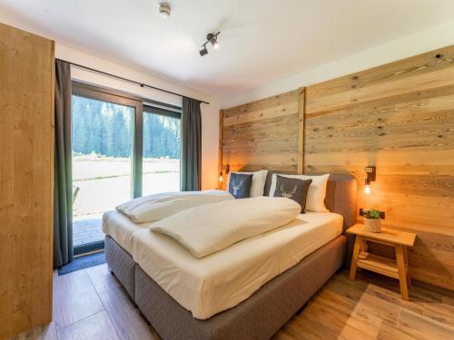 a bedroom with a large bed with a wooden wall at Almrausch in Wald im Pinzgau