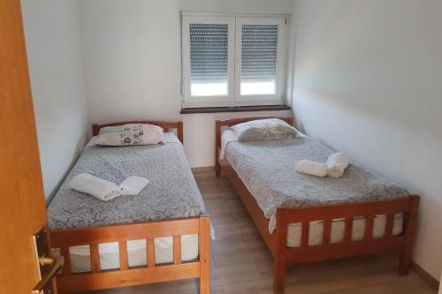 two beds in a small room with a window at Apartment Ugljan 846b in Ugljan