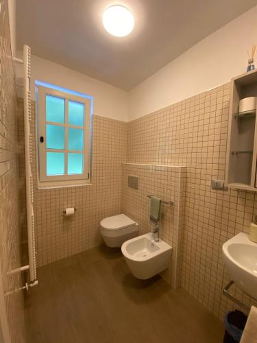 a bathroom with a toilet and a sink and a window at AFFITTACAMERE PIAZZA UNITA' in Monfalcone