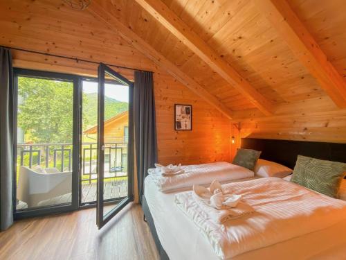 two beds in a room with a large window at Rattendorf 22A in Rattendorf
