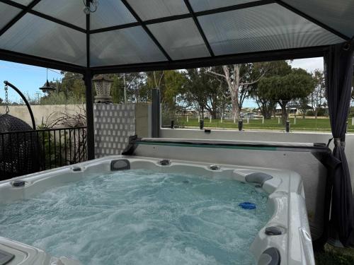 a hot tub with an umbrella in a backyard at Waterlink Retreat in South Yunderup