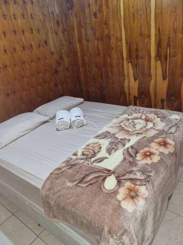 a bed with shoes and a blanket on it at Casa Da Chácara in Prudentópolis
