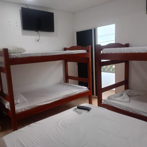 a room with three bunk beds and a television at HOTEL ALMARr in Coveñas