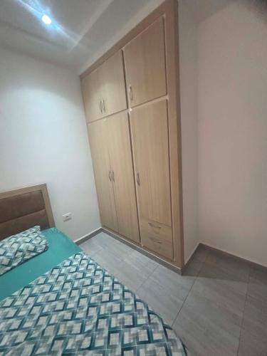 a bedroom with a bed and wooden cabinets at Résidence ADAM in Akouda