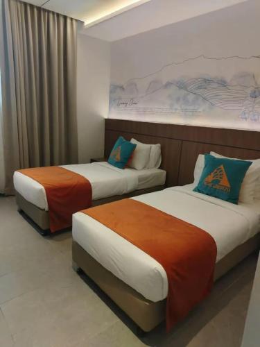 two beds sitting next to each other in a room at The Jerai Hotel Sungai Petani in Sungai Petani