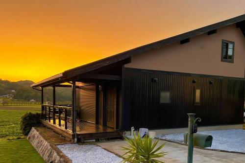 a house with a deck with a sunset in the background at Setouchi Retreats Sera Highlands in Egi