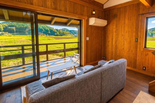 a living room with a couch and a large window at Setouchi Retreats Sera Highlands in Egi