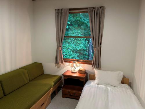 a room with a couch and a bed and a window at Guesthouse Lavande in Chino