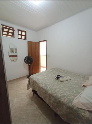 a white bedroom with a bed and a window at Aluguel de quarto com suite in Aracaju