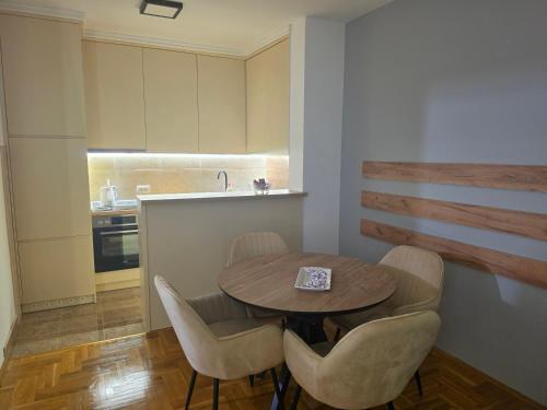 a kitchen with a wooden table and chairs and a kitchen with a sink at Apartman BIANKA in Bijeljina