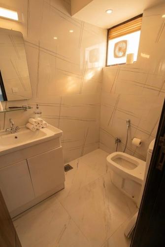 a white bathroom with a sink and a toilet at Cecil Apartments On Mall Road Murree in Murree