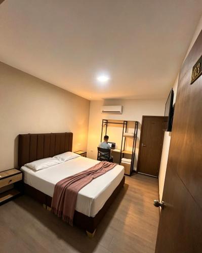 a bedroom with a bed and a person sitting on a desk at Hotel Gallery By 70 in Medellín