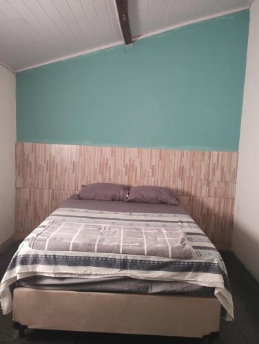 a bed in a room with a blue wall at Rosane's casa in Guapimirim
