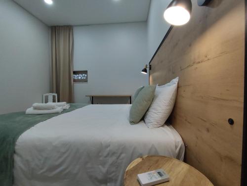 a bedroom with a large white bed with a wooden headboard at Barcelos Habadia Adega in Lijó