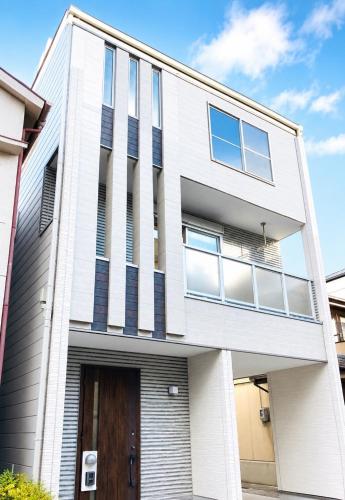 a white house with a brown door at Rest one room大阪-阪急梅田駅から電車と徒歩で15分-神崎川駅から徒歩7分- in Osaka