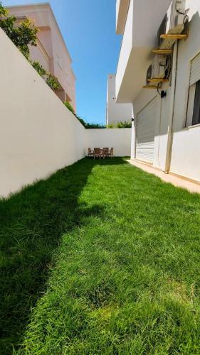 a courtyard of a building with chairs in the grass at Résidence petit paris RDC2 in Kelibia