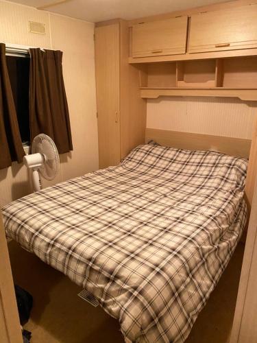 a small room with a bed with a plaid blanket at Ingoldmells holiday in Ingoldmells