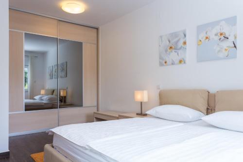 a bedroom with a white bed with a large mirror at Apartments Villa Alba in Dubrovnik