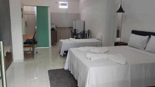 two beds in a white room with towels on them at Suíte Lençóis - Quarto amplo com Cozinha Integrada in Lençóis