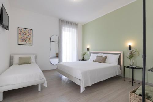 a white bedroom with two beds and a window at Dimore Margherita in Petacciato
