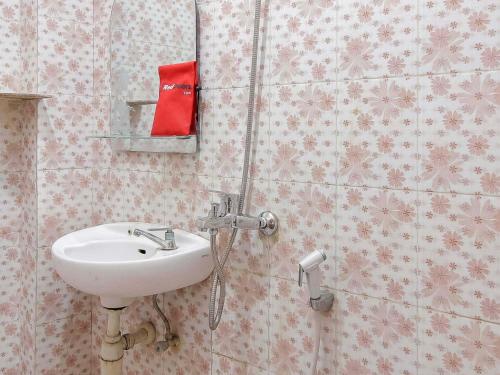a bathroom with a sink and a red box on the wall at RedDoorz @ Malalayang Manado in Manado