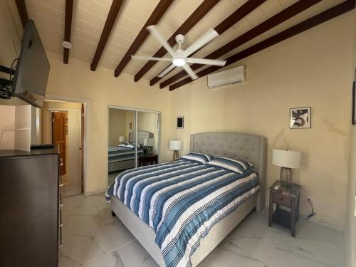 a bedroom with a bed and a ceiling fan at Villadeco Escape, Gated Cottage with Generator in West End