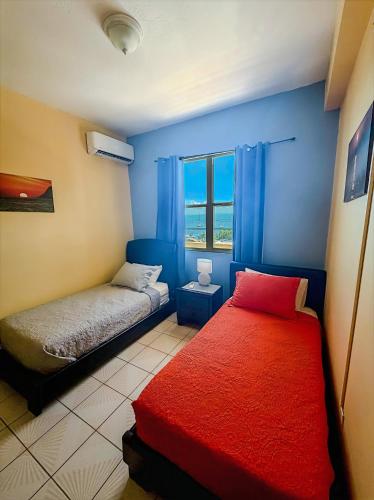 a bedroom with two beds and a red blanket at Sueños del Mar in Fajardo