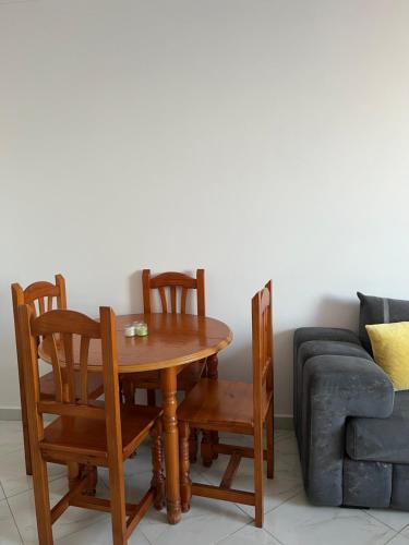 a wooden table with four chairs and a couch at Mdiaq in M'diq