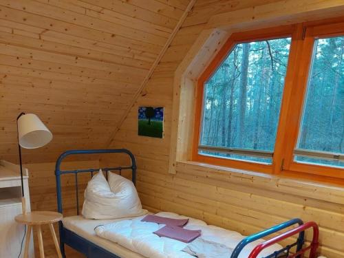 a bed in a log cabin with a window at Forest park at Roofensee in Stechlin