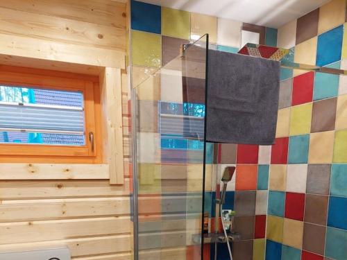 a bathroom with a shower and a colorful tiled wall at Forest park at Roofensee in Stechlin