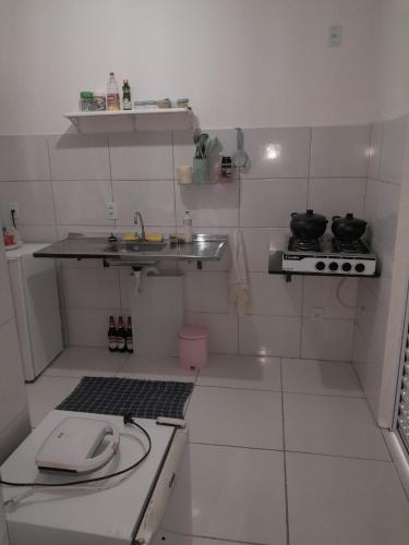 a small white kitchen with a sink and a stove at Reserva Aconchegante perto Praias, Aeroporto, UFDPar, UESPi in Parnaíba