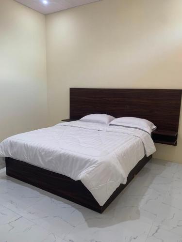 a bedroom with a large bed with a wooden headboard at Semar Hotel in Tjakranegara
