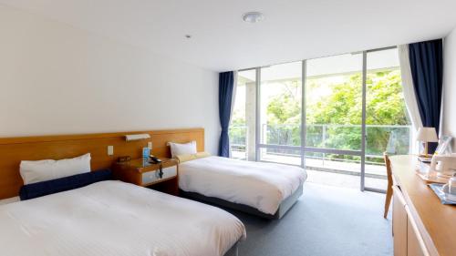 two beds in a room with a large window at TOTO Seawind Awaji in Awaji