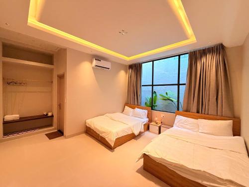 a hotel room with two beds and a window at Villa Pii-House in Ấp Sung Xuân