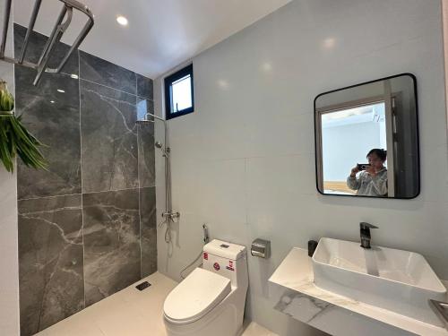 a person taking a picture of a bathroom with a toilet and sink at Villa Pii-House in Ấp Sung Xuân