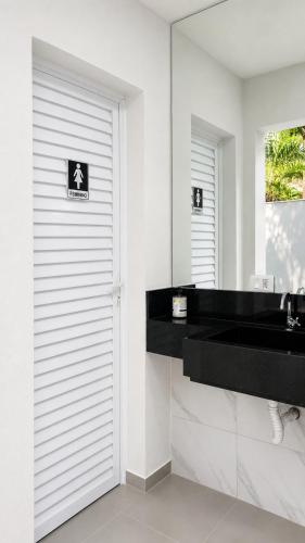 a bathroom with a door with a sink and a mirror at Recanto Veraneio in Londrina