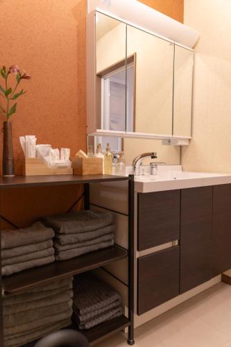 a bathroom with a sink and a mirror and towels at Yanagiya Iri in Nakatsugawa