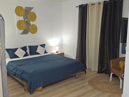 a bedroom with a bed with a blue comforter at Paradies Caraïbes II in Les Abymes