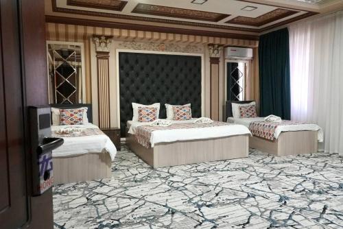 a room with three beds and a television in it at Amor fati hotel Tashkent in Katartal