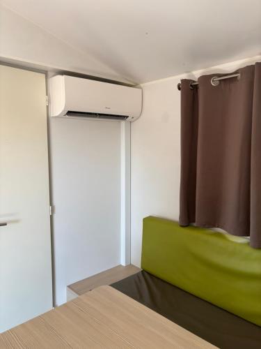 a bedroom with a green bed and a window at Mobile home climatisé 4 personnes proche Europapark in Vogelgrun