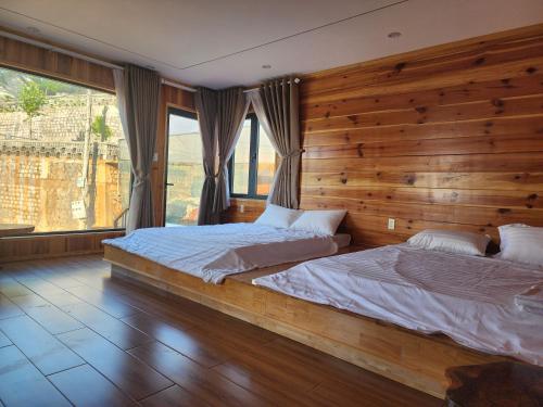 a bedroom with two beds and a wooden wall at Coffee Myhome in Kon Rung (1)