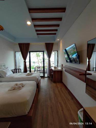 a hotel room with two beds and a television at Wisma SIDAPORE JD in Lamobuang