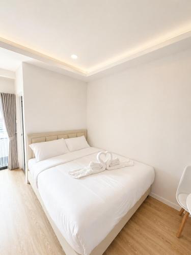 a bedroom with a white bed with a bow on it at เจฮอนโด อพาร์ตเมนต์ in Ban Si Than