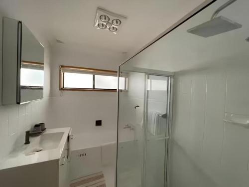 a bathroom with a glass shower and a sink at Cheerful Beach house at Redhead - BBQ, Beach, Views in Redhead