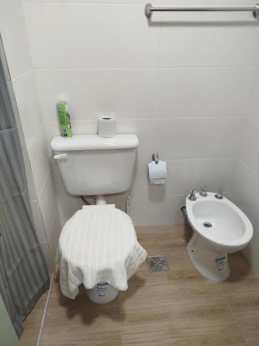 a white bathroom with a toilet and a sink at Departamento bonito con balcón in La Banda