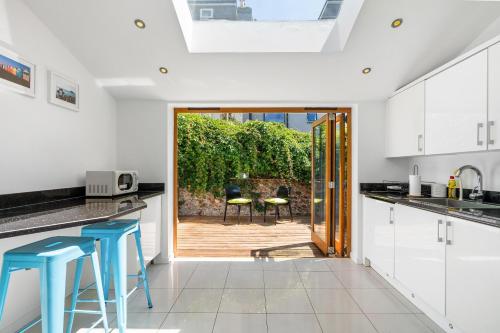 a kitchen with white cabinets and blue stools at Leafy Haven By My Getaways in Brighton & Hove