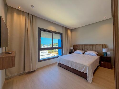 a bedroom with a bed and a large window at Résidence Oscar - Pool & View in M'diq